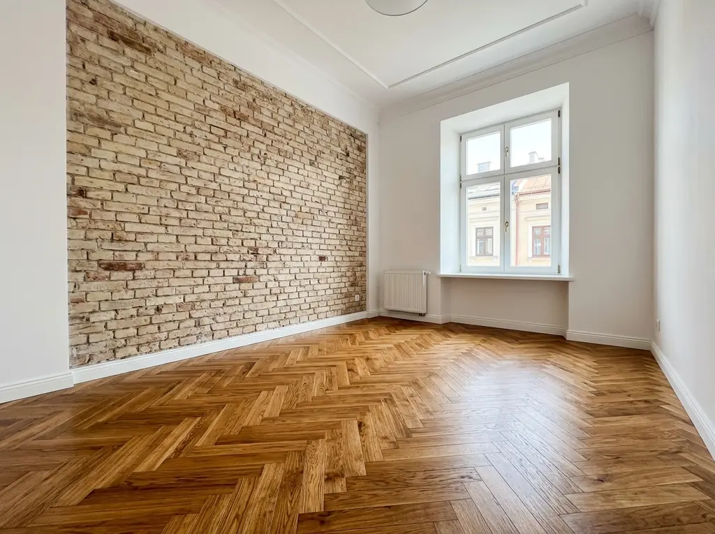 Odrestaurowany dębowy parkiet w jodełkę w kamienicy ze ścianą z jasnej cegły